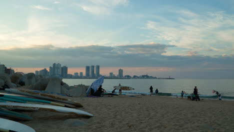 Surfing-Boards-And-People-Relaxing-During-Sunset-In-Sokcho-Beach,-South-Korea