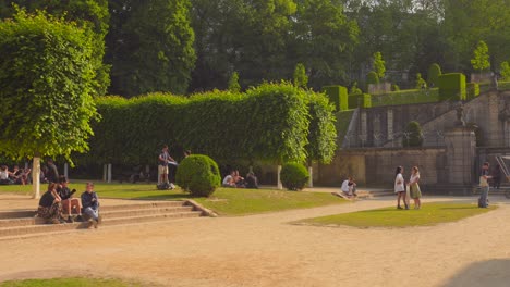 Toma-De-Jardín-De-Estudiantes-Universitarios-Sentados-En-La-Abadía-Cumbre,-Cubierto-De-Vegetación-Verde-En-Bruselas,-Bélgica-En-Un-Día-Soleado