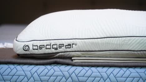 Ein-Brandneues-Weißes-Bettgear-Logo-Mit-Performance-Technologie,-Kühlendes,-Schmutzabweisendes-Kissen,-Schlafkissen-Auf-Einem-Bett-In-Einem-Matratzenladen