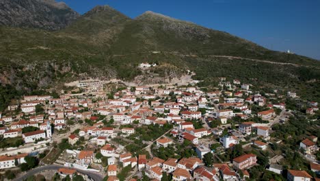 Dhermi-Mediterranean-village,-with-traditional-stone-houses-and-white-church-on-hill-surrounded-by-mountains-on-seaside-of-Albania