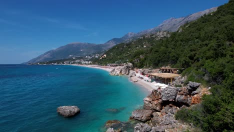 Hidden-beach-on-rocky-coastline-of-Ionian-sea-in-Albania,-turquoise-clean-sea-and-white-sand,-sunny-summer-vacation-destination