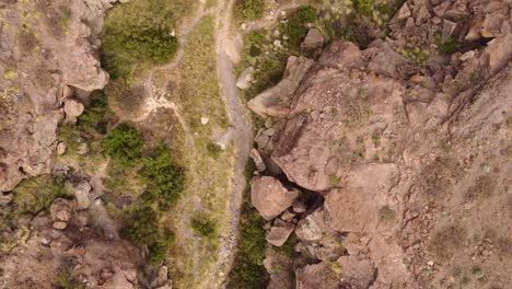 Looking-down-at-Arco-de-Tajao,-flying-above-dry-desertic-riverbed-ravine