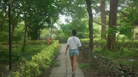 Young-female-in-short-summer-wear-has-a-leisurely-walk-in-botanical-garden