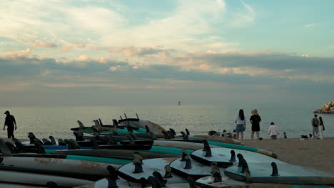 Tourists-At-Seacoast-With-Pile-Of-Surfboards-During-Sunset-In-Sokcho-Beach,-South-Korea