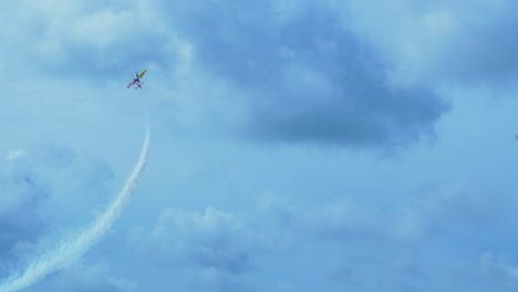 Sukhoi-Su-26-aerobatic-airplane-carrying-out-dynamic-maneuvers-in-front-of-spectators-at-Baltic-airshow-in-Liepaja,-Latvia,-white-smoke-trails,-handheld-tracking-shot,-4k