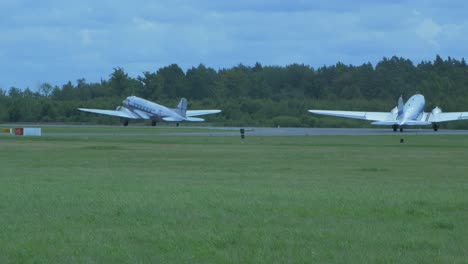 Zwei-Silberne-Und-Blaue-Douglas-DC3-Treten-Auf-Der-Baltic-International-Airshow-Auf,-Steuern-Auf-Der-Landebahn,-Blick-Vom-Boden,-Handgeführte-4K-Aufnahme