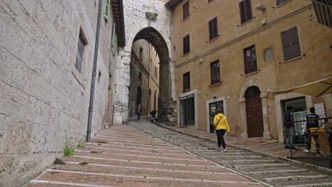 A-lone-female-tourist-walks-the-old-stairs-of-the-old-city-of-Perugia,-Province-of-Perugia,-Italy