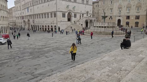 A-lone-female-walks-towards-the-Piazza-IV-Novembre-down-the-stairs-outside-the-the-entrance-of-the-Perugia-Cathedral-in-Perugia,-Province-of-Perugia,-Italy