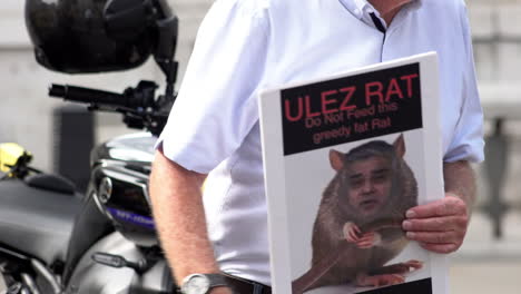 Eine-Person,-Die-Gegen-Die-Ultra-Emissionszone-Protestiert,-Hält-Ein-Plakat-In-Der-Hand,-Auf-Dem-Bürgermeister-Sadiq-Khan-Als-Ratte-Abgebildet-Ist