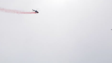 RedBull-BO-105-aerobatic-helicopter-demonstrating-stunts-at-Baltic-International-Airshow,-red-smoke-trail,-handheld-shot,-4k