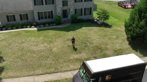 UPS-driver-and-package-runner-returning-to-vehicle-after-dropping-package-off-on-front-porch-of-large-American-home