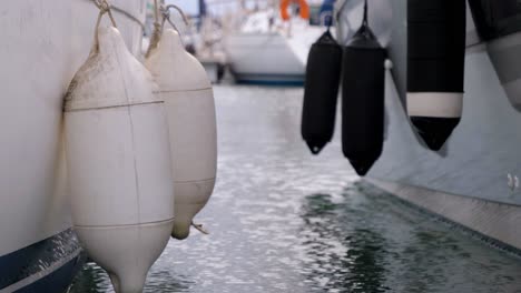 Slow-motion-panning-shot-of-buoys-hanging-off-the-side-of-a-boat-docked-in-a-port