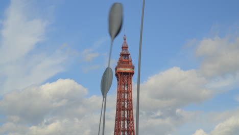 Blackpool-Tower-with-tall-seed-sculptures-swaying-in-wind-and-clouds-massing-behind-on-summer-day