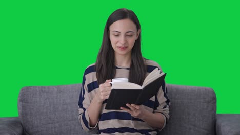 Happy-Indian-girl-reading-book-and-drinking-coffee-Green-screen