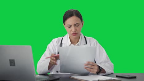 Doctora-India-Estresada-Revisando-Informes-Médicos-Pantalla-Verde