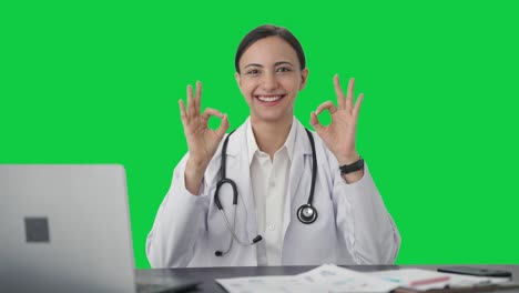 Happy-Indian-female-doctor-showing-okay-sign-Green-screen