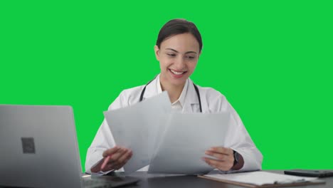 Fröhliche-Indische-Ärztin-überprüft-Medizinische-Berichte-Auf-Grünem-Bildschirm