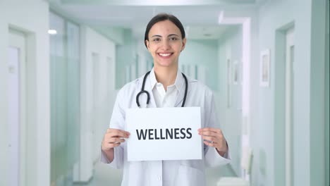Happy-Indian-female-doctor-holding-WELLNESS-banner