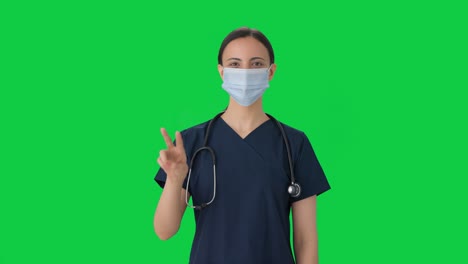 Fröhliche-Indische-Ärztin-Zeigt-Siegeszeichen-Mit-Maske-Auf-Grünem-Bildschirm