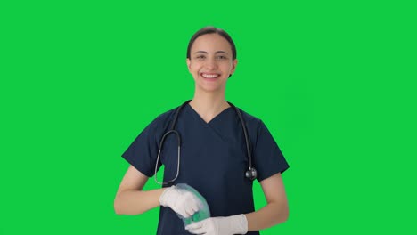 Fröhliche-Indische-Ärztin,-Die-Handschuhe-Und-Mütze-Auszieht,-Grüner-Bildschirm