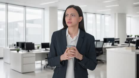 Worried-Indian-female-manager-waiting-for-someone-and-drinking-coffee