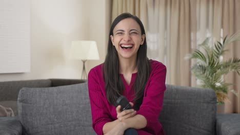 Happy-Indian-woman-laughing-while-watching-TV