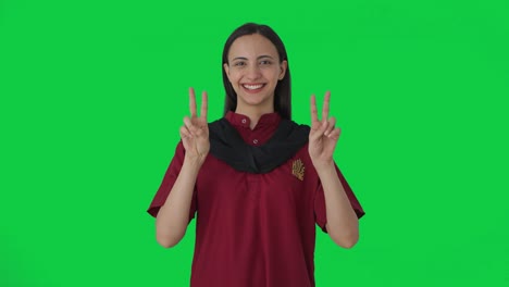 Happy-Indian-female-housekeeper-showing-victory-sign-Green-screen
