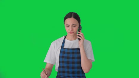 Indian-housewife-talking-on-call-while-making-food-Green-screen
