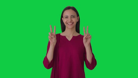 Happy-Indian-female-teacher-showing-victory-sign-Green-screen