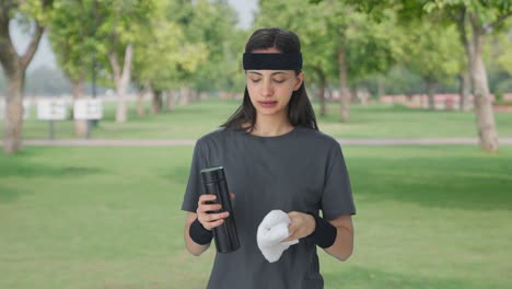 Indian-girl-wiping-sweat-and-drinking-water-after-workout