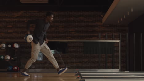One-black-African-American-man-throws-a-bowling-ball-and-knocks-out-a-clash-dancing-jumping-and-singing-rejoicing-in-victory