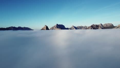 Rocky-peaks-of-massive-mountains-in-fluffy-clouds