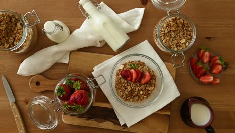 Faceless-person-decorating-muesli-with-fresh-strawberries-in-kitchen