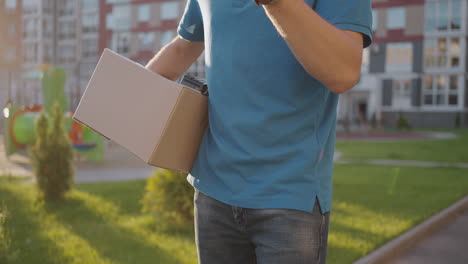 Delivery-Hand-of-young-man-pays-for-purchases-using-the-contactless-payment-nfs-system.-Young-delivery-man-hold-package-man-client-paying-by-phone-for-parcel-transporting-payment-uniform-express-order