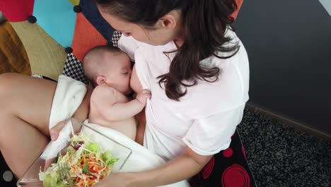 Woman-breastfeeding-baby-with-bowl-of-salad-in-hands