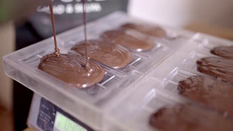 Crop-chocolatier-pouring-melted-chocolate-into-form-in-kitchen