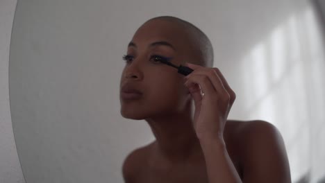 Serious-black-woman-applying-mascara-on-eyelashes