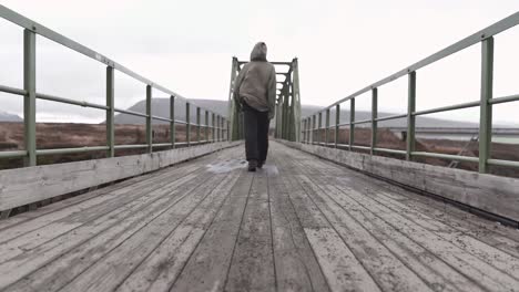 Anonymous-man-standing-on-bridge-in-gloomy-day