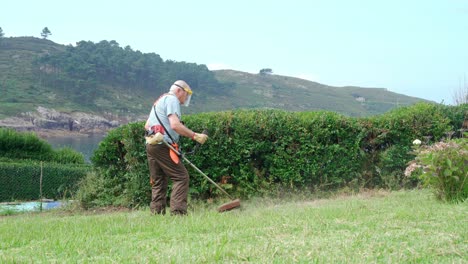 Älterer-Mann-Mit-Schutzschildmaske-Mäht-Gras-Mit-Rasenmäher