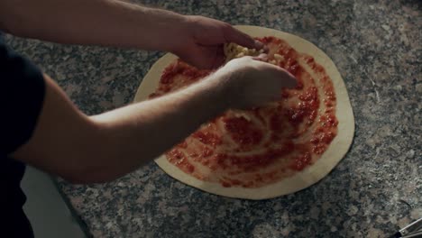 Anonymous-man-adding-cheese-to-pizza