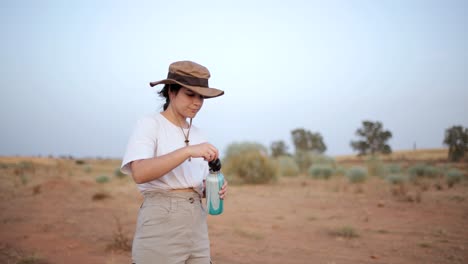 Woman-drinking-water-in-desert-field