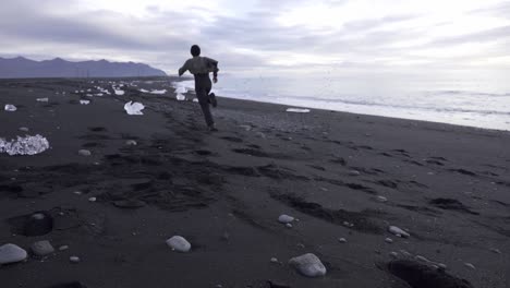 Man-running-along-seashore-in-winter
