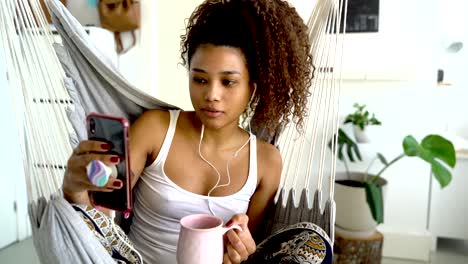 Young-black-woman-with-earphones-taking-selfie-at-home