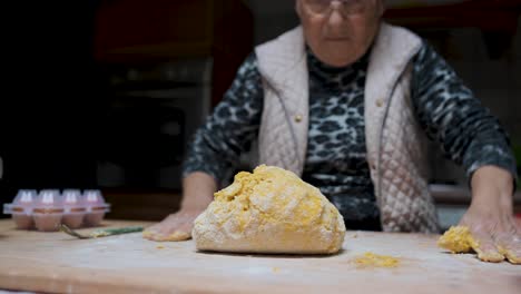 Aged-woman-kneading-dough-in-kitchen