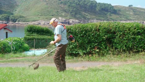 Senior-man-in-protective-shield-mask-mowing-grass-with-mower