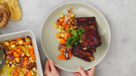 Crop-female-serving-ribs-with-vegetables-on-table