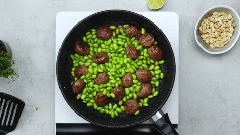 Woman-adding-green-beans-to-meatballs