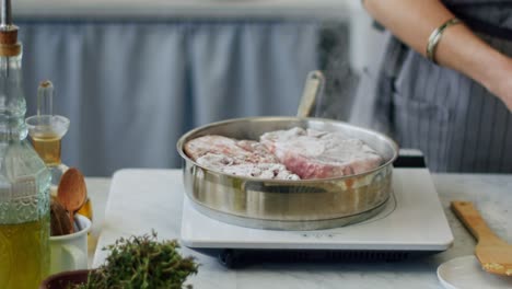 Woman-putting-raw-beef-in-frying-pan-on-electric-stove