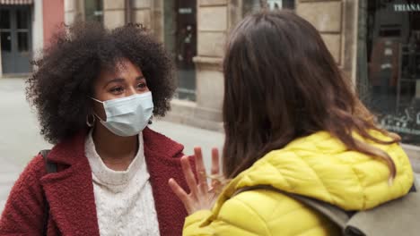 Multiethnic-women-in-masks-talking-to-each-other-on-street