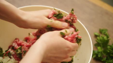 Crop-person-mixing-ground-meat-with-herbs-and-garlic